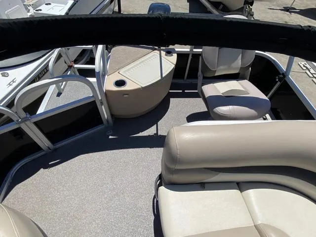 Slide: The Image of 2015 Sun Tracker 18 DLX pontoon boat interior with beige seating and table. - 9