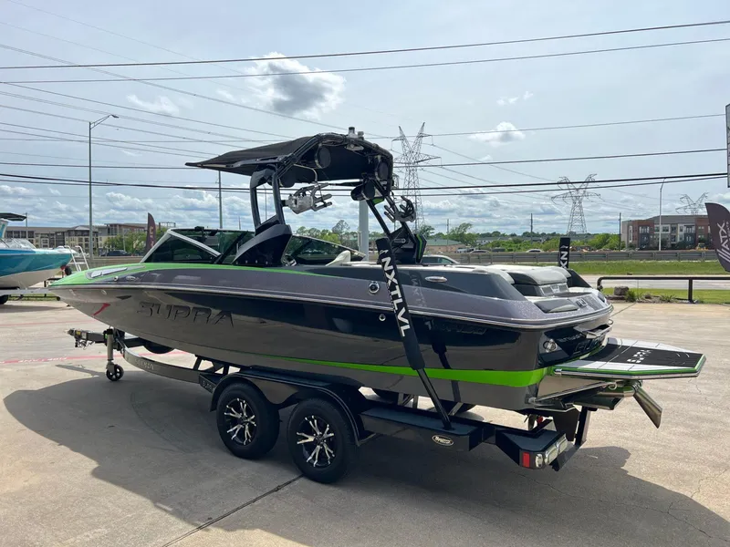 Slide: The Image of 2014 Supra SA450 boat on trailer, black and green design, parked outdoors. - 22
