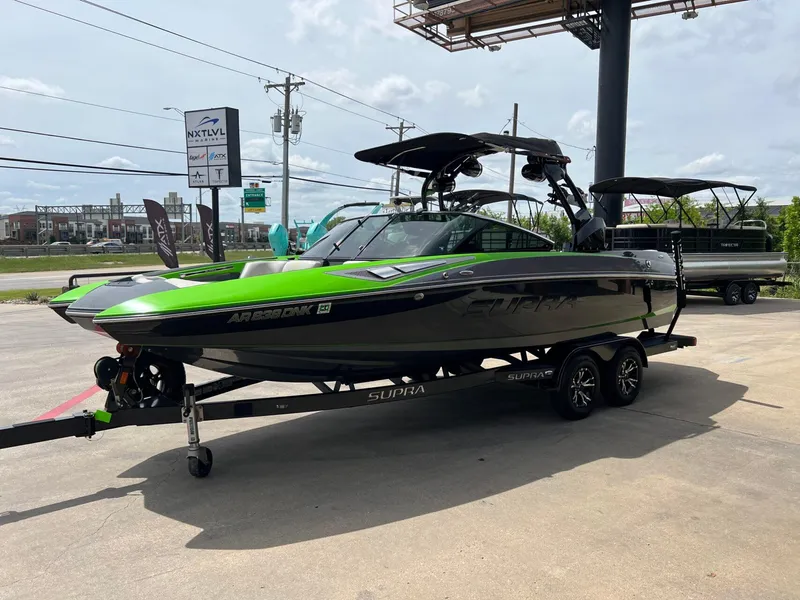 Slide: The Image of 2014 Supra SA450 boat with vibrant green accents on a trailer at a dealership. - 24