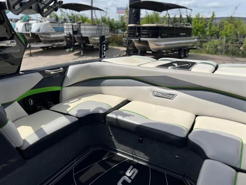 Slide: The Image of 2014 Supra SA450 boat interior with white and green seating, docked near other boats. - 8