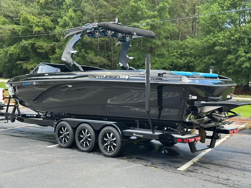 Slide: The Image of 2019 Centurion Ri257 boat on trailer, parked outdoors with lush greenery in background. - 19