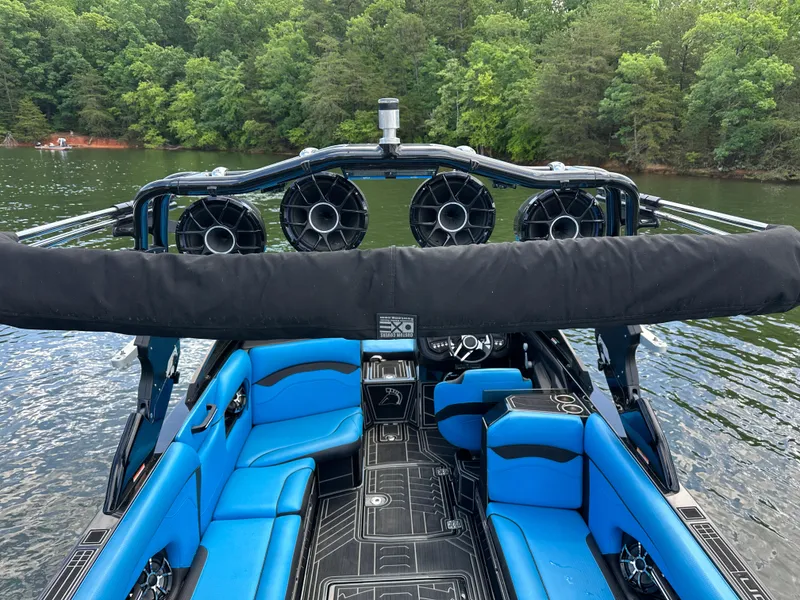 Slide: The Image of 2019 Centurion Ri257 boat with blue seating, on a lake surrounded by trees. - 7