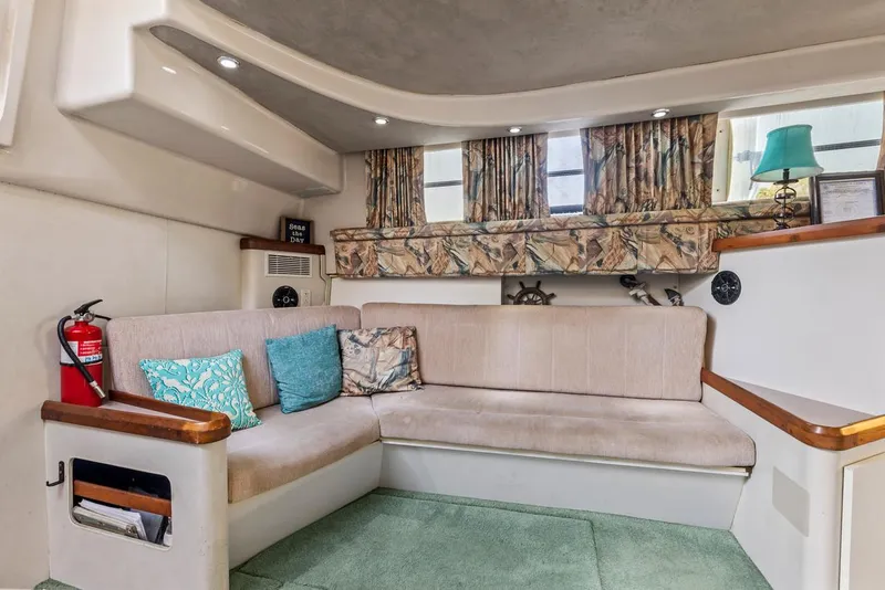 Slide: The Image of 1996 Mainship 37 Aft Cabin interior with beige seating, decorative pillows, and nautical decor. - 16