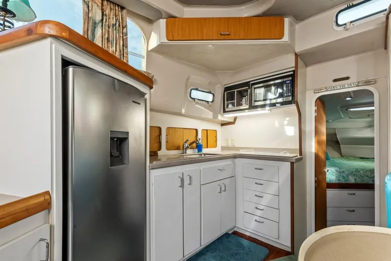 Slide: The Image of 1996 Mainship 37 Aft Cabin interior with modern kitchen, stainless steel fridge, and ample storage. - 21