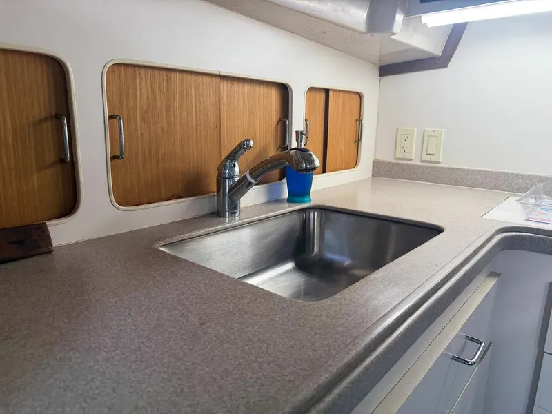 Slide: The Image of 1996 Mainship 37 Aft Cabin kitchen with stainless steel sink and wooden cabinets. - 23