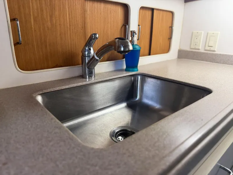 Slide: The Image of 1996 Mainship 37 Aft Cabin kitchen sink with faucet and wooden cabinets. - 24