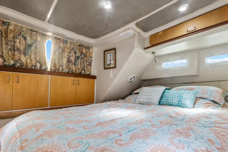 Slide: The Image of 1996 Mainship 37 Aft Cabin bedroom with cozy bedding, wooden cabinets, and natural light. - 29