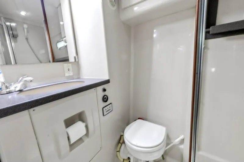 Slide: The Image of 1996 Mainship 37 Aft Cabin bathroom with toilet, sink, and shower area. - 31