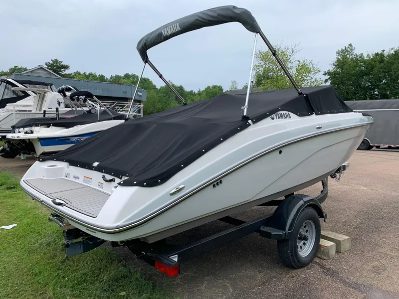 Slide: The Image of 2023 Yamaha SX195 boat on trailer with black cover, parked outdoors. - 11