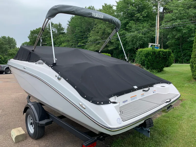 Slide: The Image of 2023 Yamaha SX195 boat with cover on trailer, parked outdoors. - 12