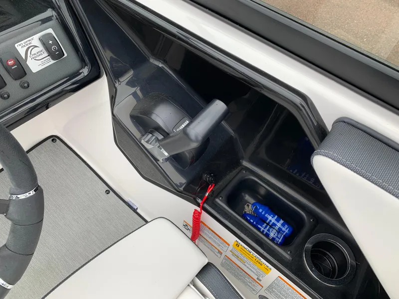 Slide: The Image of 2023 Yamaha Boats SX195 cockpit controls with throttle, switches, and storage compartment. - 21