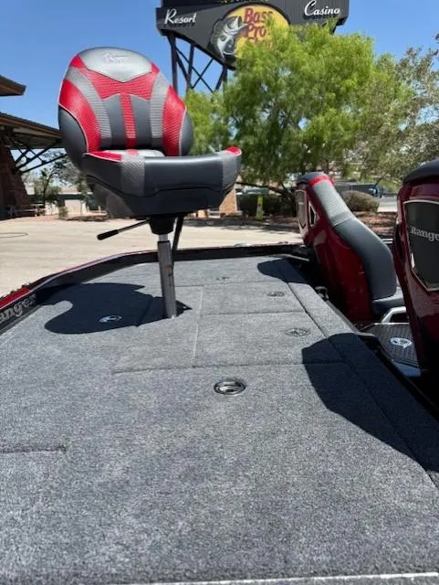 Slide: The Image of 2025 Ranger Z521R boat with red and gray seating, parked outdoors near a resort. - 10
