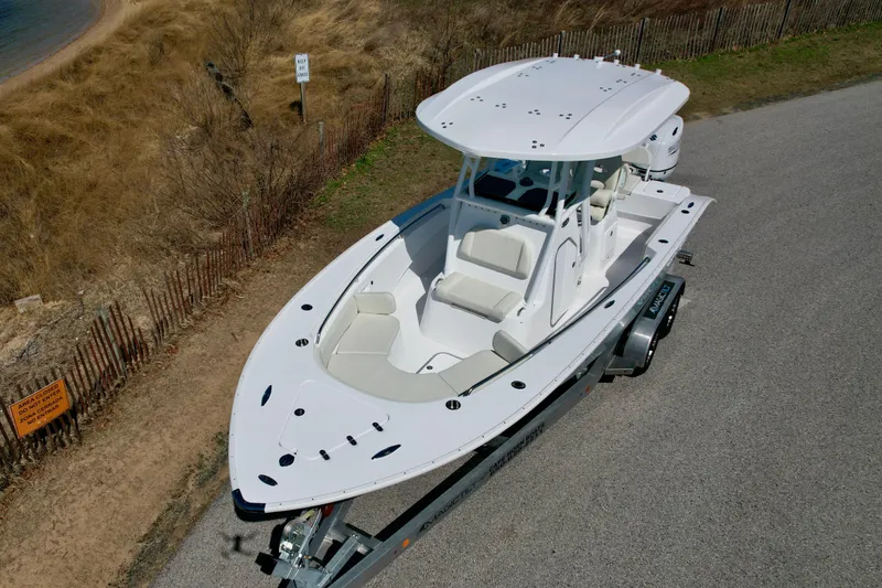 Slide: The Image of 2025 Cape Horn 24 XS boat on trailer, parked near a sandy beach. - 12