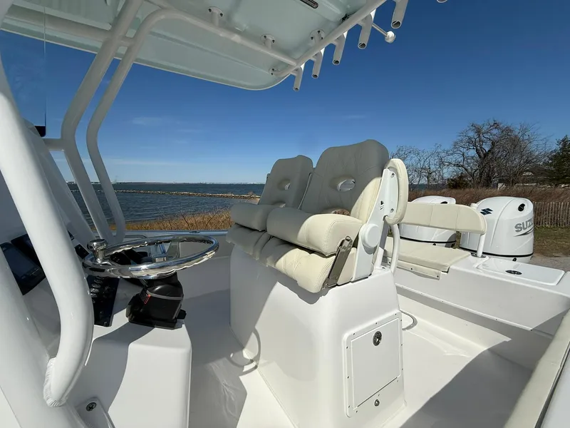 Slide: The Image of 2025 Cape Horn 24 XS boat interior with dual seats and steering wheel, near water. - 20