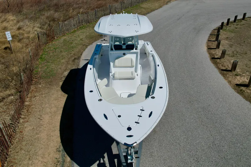 Slide: The Image of 2025 Cape Horn 24 XS boat on a trailer, parked on a road near a grassy area. - 9