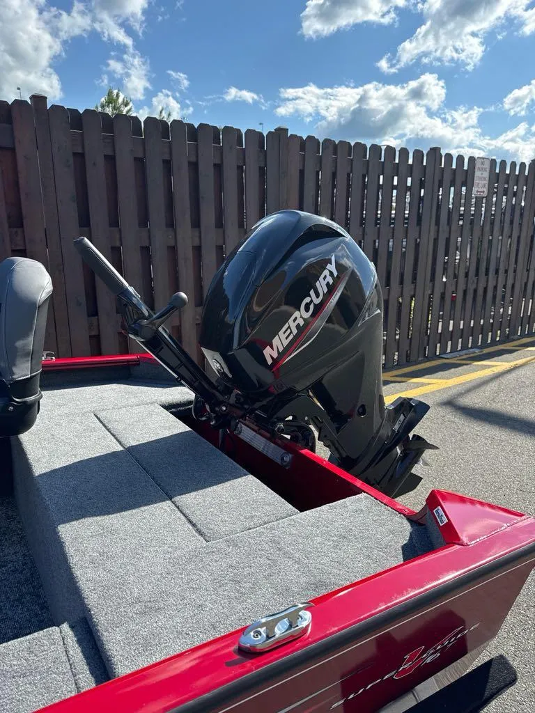 Slide: The Image of 2025 Tracker Super Guide V-16 T boat with Mercury outboard motor, parked outdoors. - 2