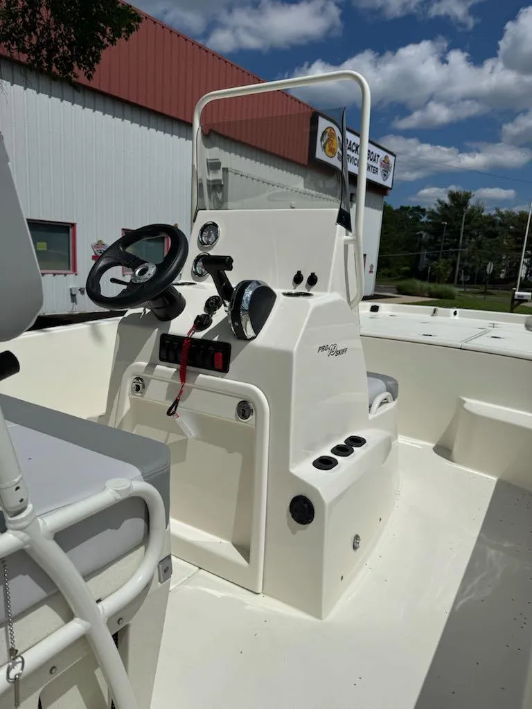 Slide: The Image of 2025 Mako Pro Skiff 19 CC boat interior with steering console under blue sky. - 10