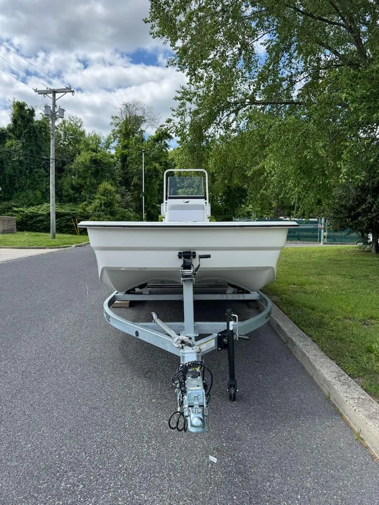 Slide: The Image of 2025 Mako Pro Skiff 19 CC boat on trailer, parked on a suburban street. - 2