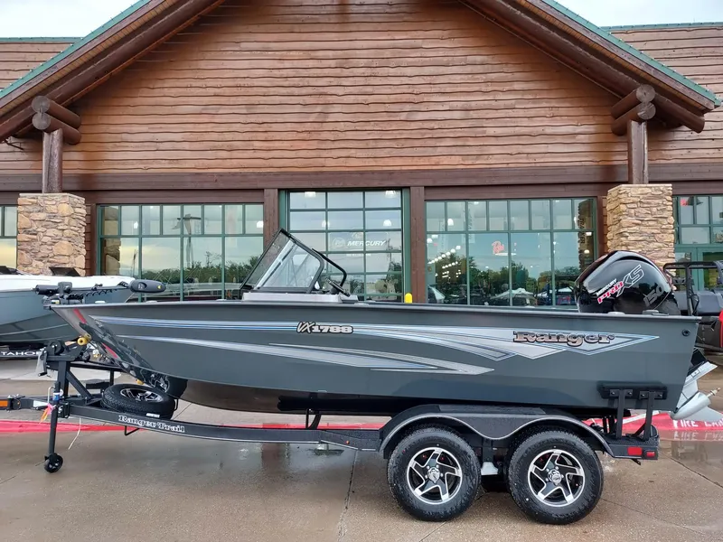 Slide: The Image of 2025 Ranger VX1788 WT boat on trailer outside a wooden building. - 0