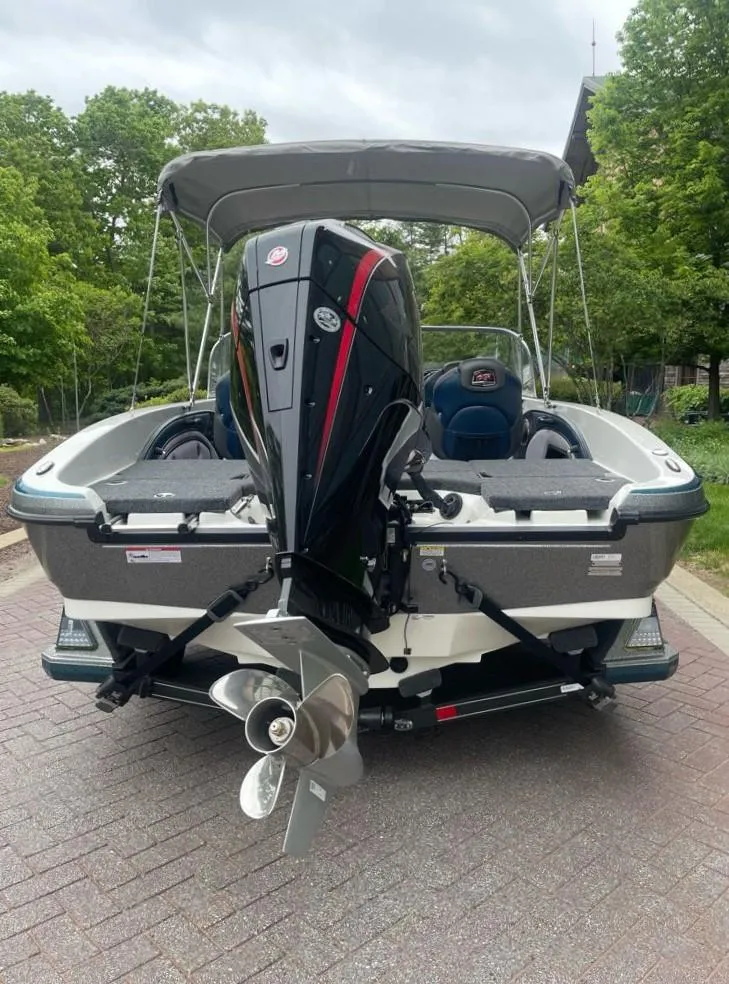 Slide: The Image of 2025 Ranger 1850MS boat with outboard motor, parked on a paved path, surrounded by trees. - 7