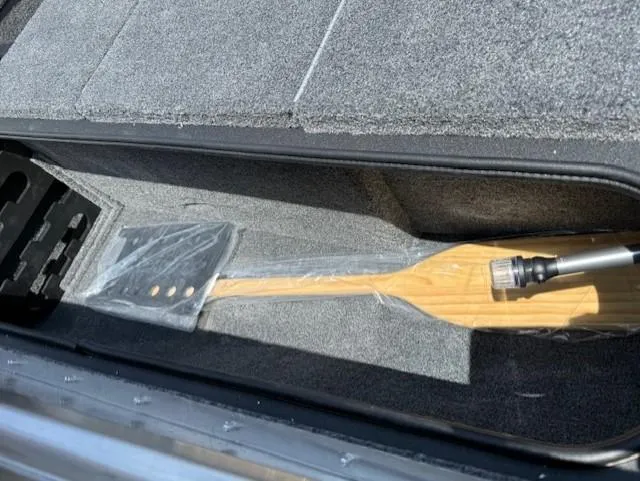 Slide: The Image of Storage compartment in 2025 Tracker Pro Team 195 Tournament Edition boat with a wooden paddle. - 11