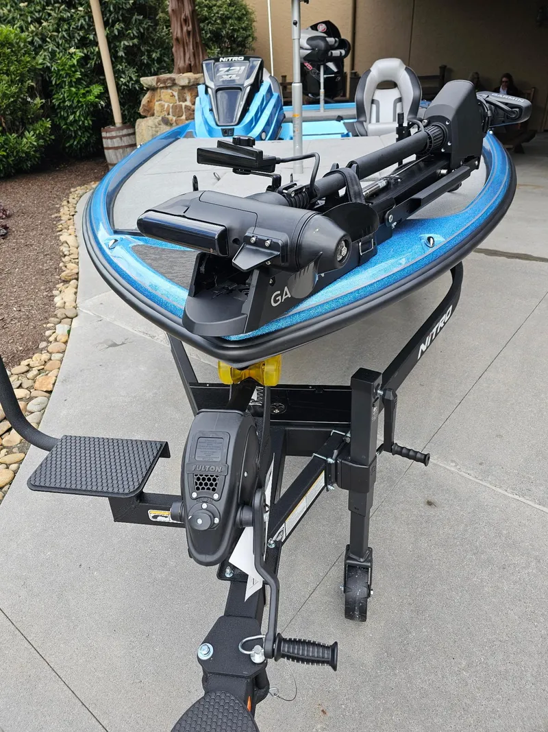 Slide: The Image of 2025 Nitro Z21 XL Pro boat on trailer, blue and black design, parked outdoors. - 2