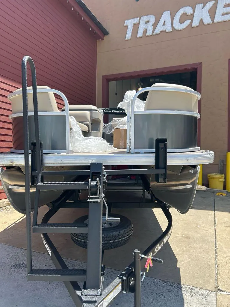 Slide: The Image of 2025 Sun Tracker Party Barge 18 DLX pontoon boat on trailer outside dealership. - 2