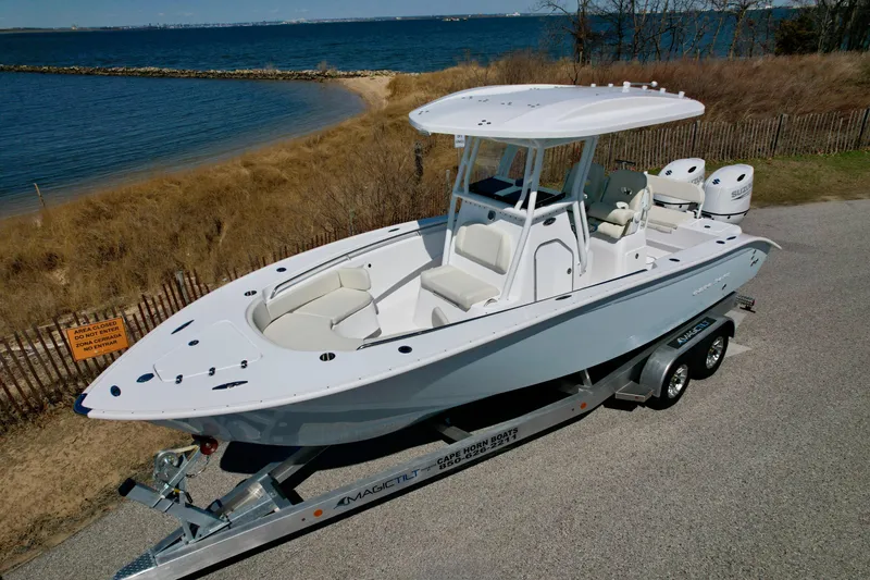 Slide: The Image of 2025 Cape Horn 24 XS boat on trailer by the coast, featuring dual engines. - 14