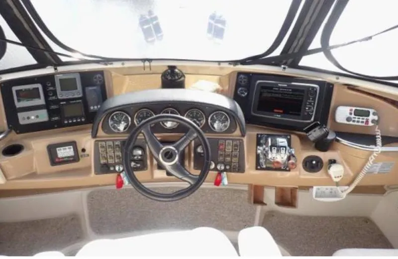 Slide: The Image of 2002 Carver 396 Motor Yacht helm with steering wheel, gauges, and navigation controls. - 17