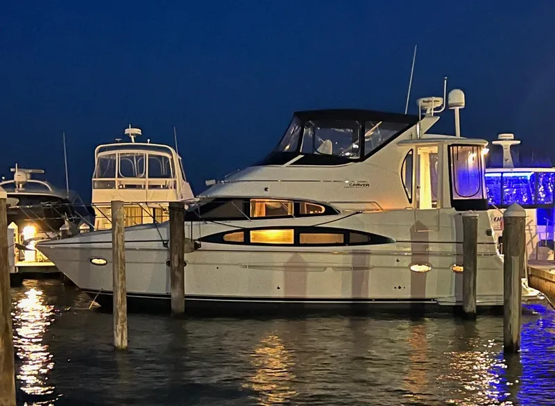 Slide: The Image of 2002 Carver 396 Motor Yacht docked at night, illuminated against a dark sky. - 6