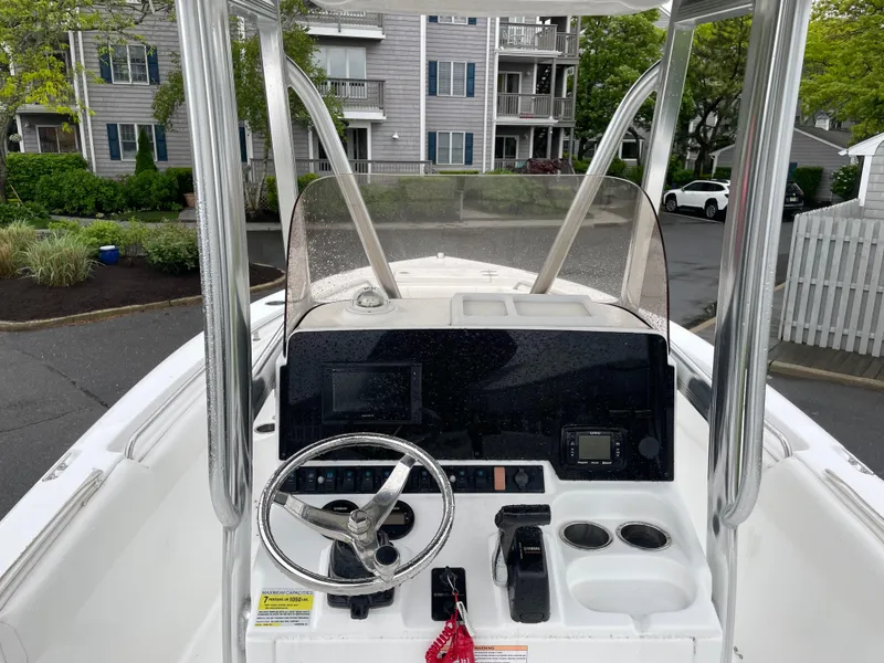 Slide: The Image of 2017 Sea Hunt 21 CC boat console with steering wheel and controls, parked near residential buildings. - 11