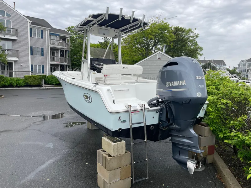 Slide: The Image of 2017 Sea Hunt 21 CC boat with Yamaha 150 engine, parked on blocks in a residential area. - 2