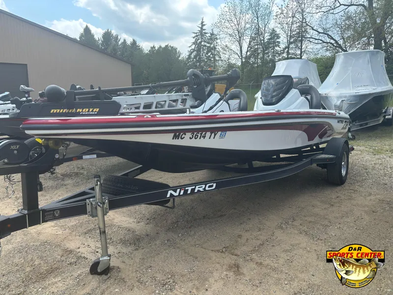 Slide: The Image of 2017 Nitro Z18 boat on trailer, parked outdoors, with cover and trees in background. - 19
