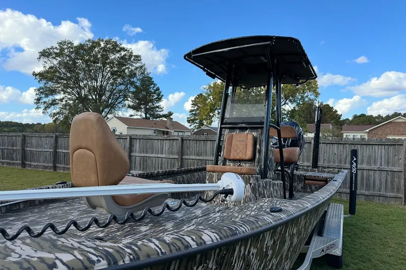 Slide: The Image of 2024 Avid 23 Mag boat with camo design, parked in a grassy yard. - 3