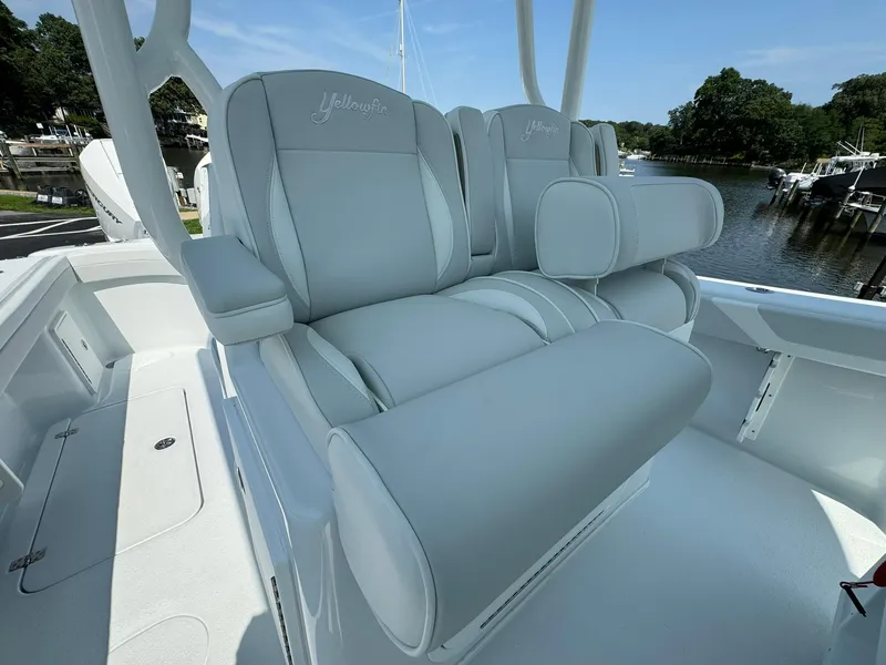 Slide: The Image of 2025 Yellowfin 34 Offshore boat with dual cushioned seats at a marina. - 18