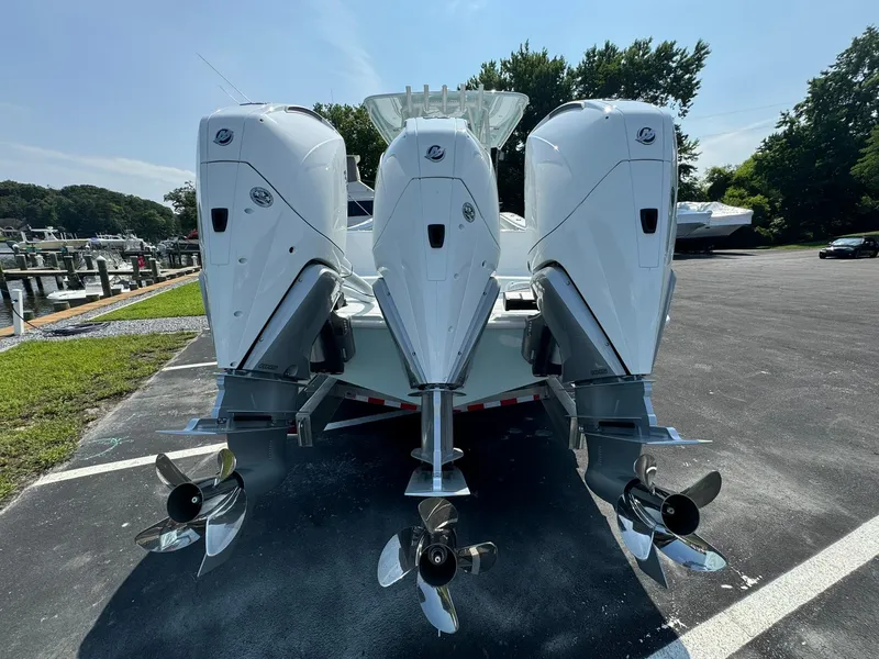 Slide: The Image of 2025 Yellowfin 34 Offshore boat with triple outboard engines in a parking area. - 6