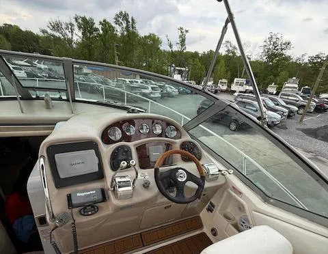 Slide: The Image of 2005 Sea Ray 320 Sundancer helm with navigation equipment and steering wheel, docked near cars. - 15