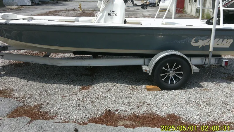 Slide: The Image of 2023 Mako 18 LTS boat on trailer, parked on gravel surface. - 0