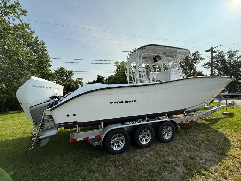 Slide: The Image of 2025 Cape Horn 32 XS boat on trailer, parked on grass, side view. - 3