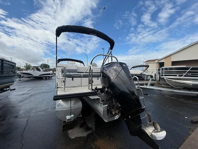 Slide: The Image of 2021 Harris Sunliner 250 pontoon boat with outboard motor, parked on wet pavement. - 11