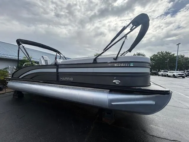 Slide: The Image of 2021 Harris Sunliner 250 pontoon boat parked on a wet surface under cloudy skies. - 2