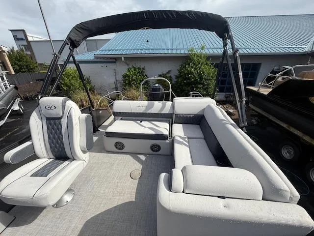 Slide: The Image of 2021 Harris Sunliner 250 pontoon boat with spacious seating and canopy, docked outdoors. - 5