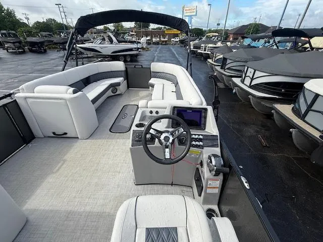 Slide: The Image of 2021 Harris Sunliner 250 pontoon boat interior with helm and seating, docked at marina. - 8