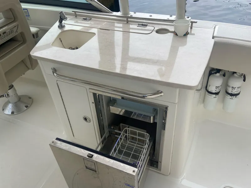 Slide: The Image of Boston Whaler 270 Vantage 2013 boat kitchenette with sink and open storage compartment. - 12