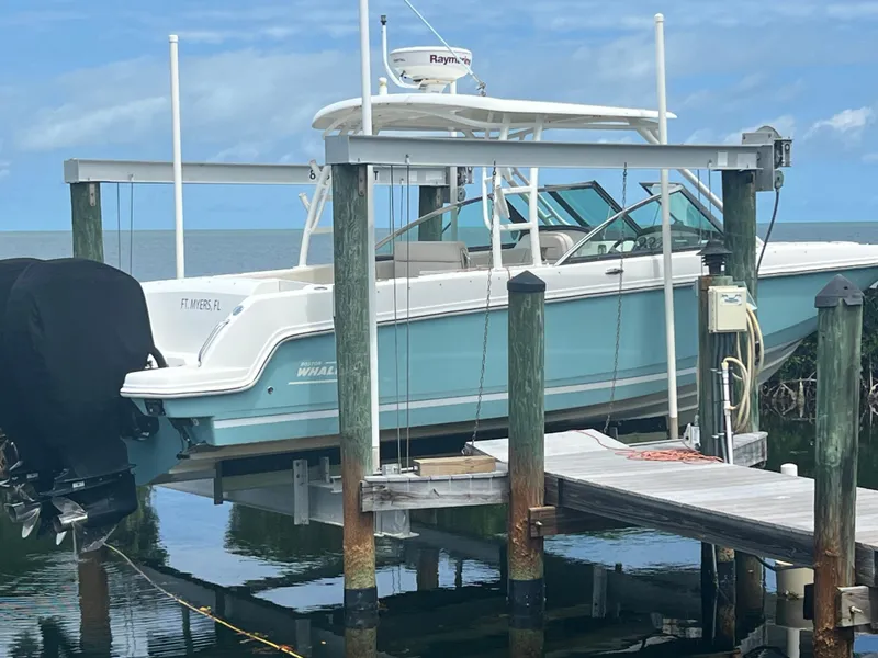 Slide: The Image of 2013 Boston Whaler 270 Vantage boat docked on a lift by the water. - 2