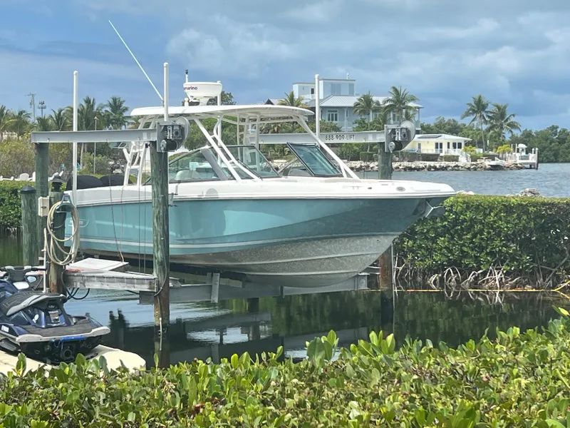 Slide: The Image of Boston Whaler 270 Vantage 2013 boat on lift by waterfront homes and lush greenery. - 4