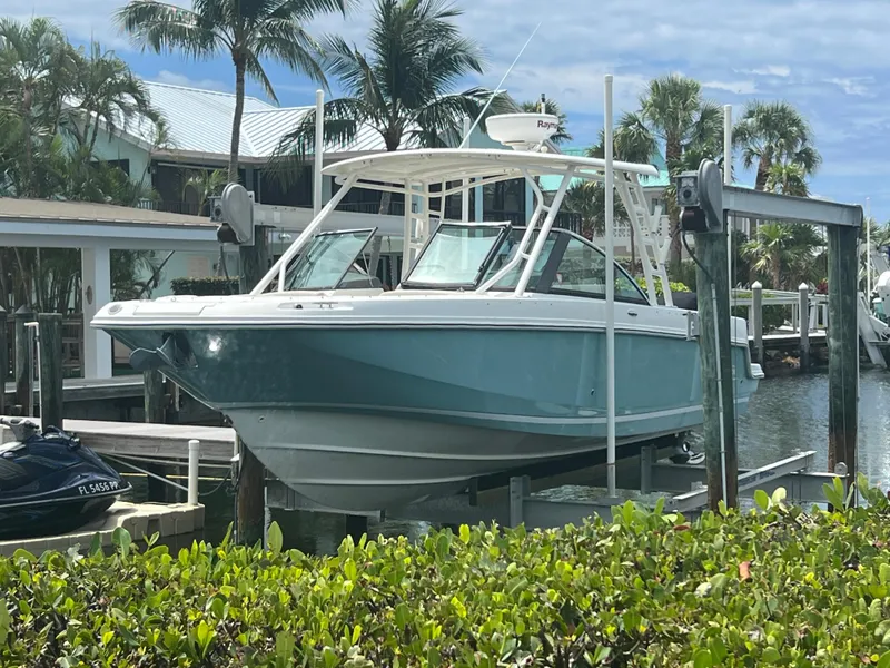 Slide: The Image of 2013 Boston Whaler 270 Vantage boat docked near palm trees and waterfront homes. - 5