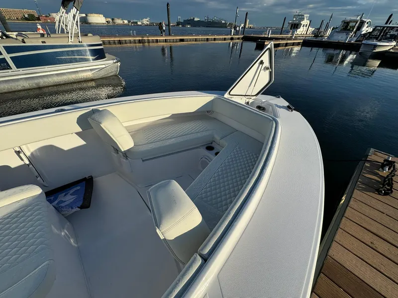 Slide: The Image of 2024 Jupiter 26 FS boat interior at marina, featuring white seating and open storage. - 7