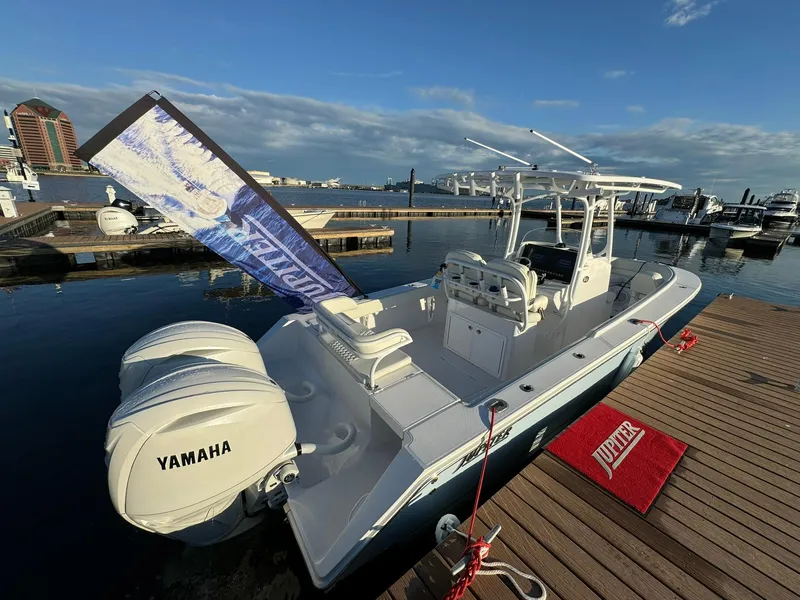 Slide: The Image of 2024 Jupiter 26 FS boat docked, featuring Yamaha engines, under a clear blue sky. - 2
