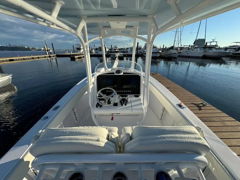 Slide: The Image of 2024 Jupiter 26 FS boat at marina, showcasing helm and seating area. - 9